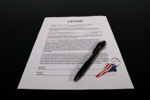 Lease agreement document with pen and American flag keychain on a black table.